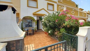 Un immeuble résidentiel doté d’un patio carrelé, d’un escalier et d’une entrée fermée par un portail.