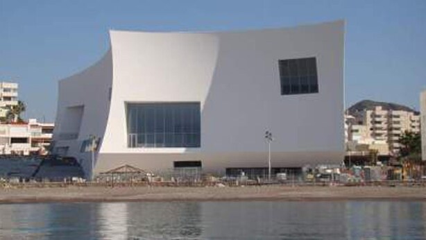 Un bâtiment moderne de couleur blanche, doté d’une architecture originale aux lignes angulaires, situé près du bord de l’eau.