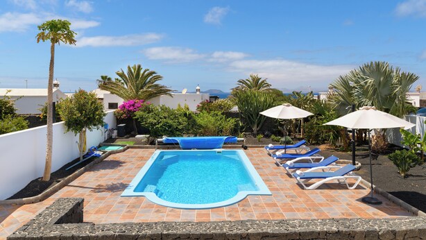 A rooftop pool area with a rectangular pool, lounge chairs, and umbrellas. - Stunning 4-bed Villa in Playa Blanca (Yaiza)
