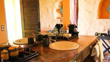 A bathroom with a marble countertop, two sinks, a mirror, and a towel rack.
