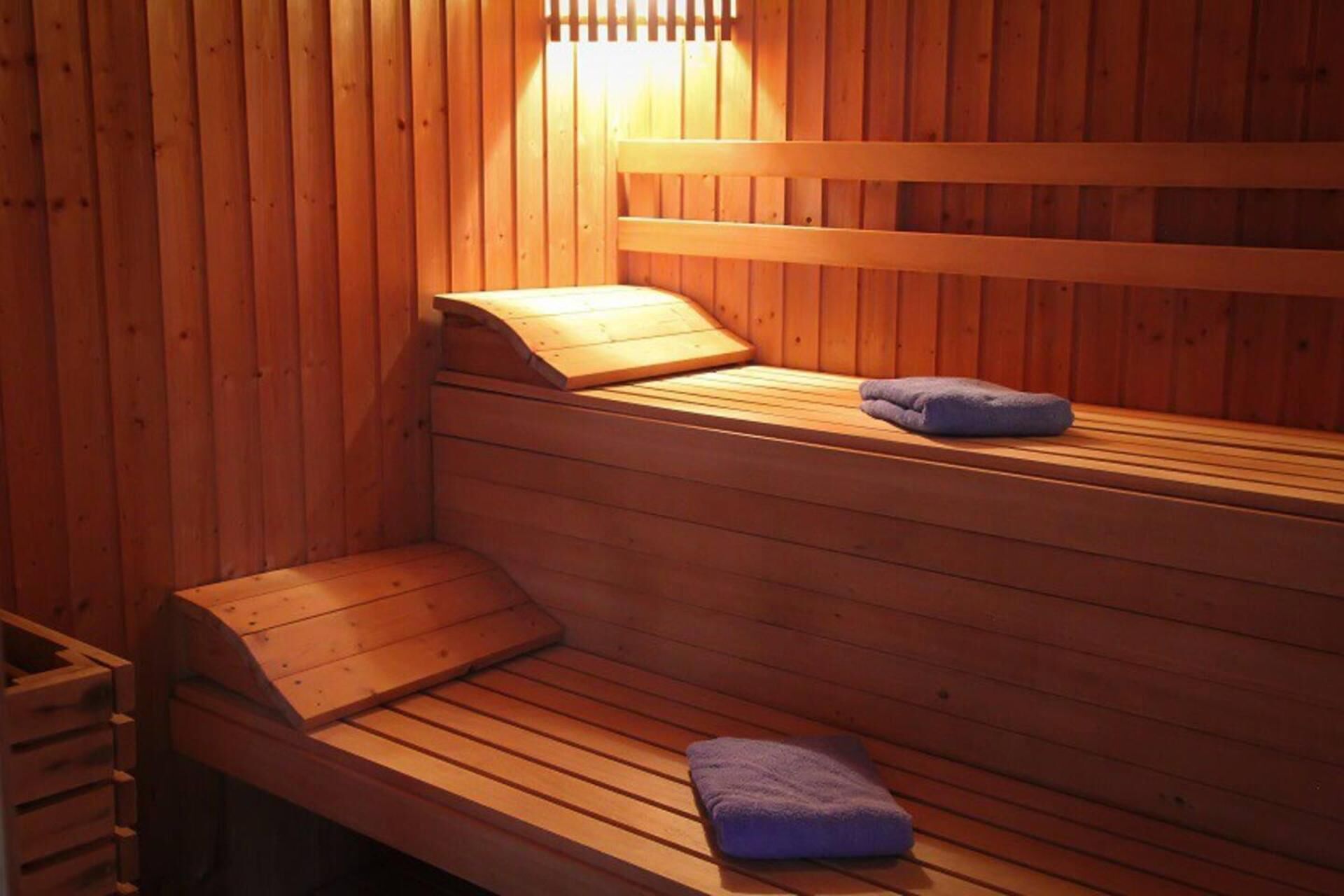 Una sauna de madera con bancos y un asiento, y una toalla en el suelo.