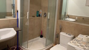 A modern bathroom with a glass-enclosed shower, a sink, and a toilet.