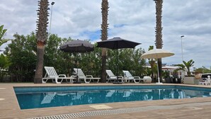 A swimming pool with lounge chairs and umbrellas, surrounded by palm trees and greenery. - 3-bed Villa Sleeps 8 With Private Pool (Santa Pola)