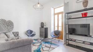 A modern living room with a grey sofa, two black wireframe chairs, a glass coffee table, and a geometric patterned rug. - Remarkable 3 Bedroom Apartment in L'eixample (Valencia)