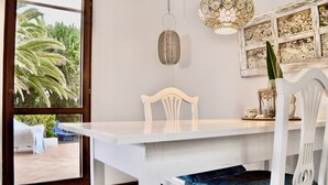 Un tavolo da pranzo bianco con un cuscino blu, una sedia bianca e una lampada a sospensione decorativa.