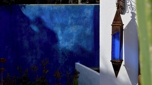 Un muro blu con un lanterne decorativo e un muro in pietra sullo sfondo.