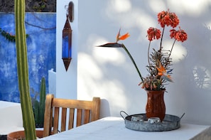 A table with a vase of flowers, a wooden chair, and a metal tray with salt and pepper shakers. - Stylish House in a Real Finca With Private Garden (Yaiza)