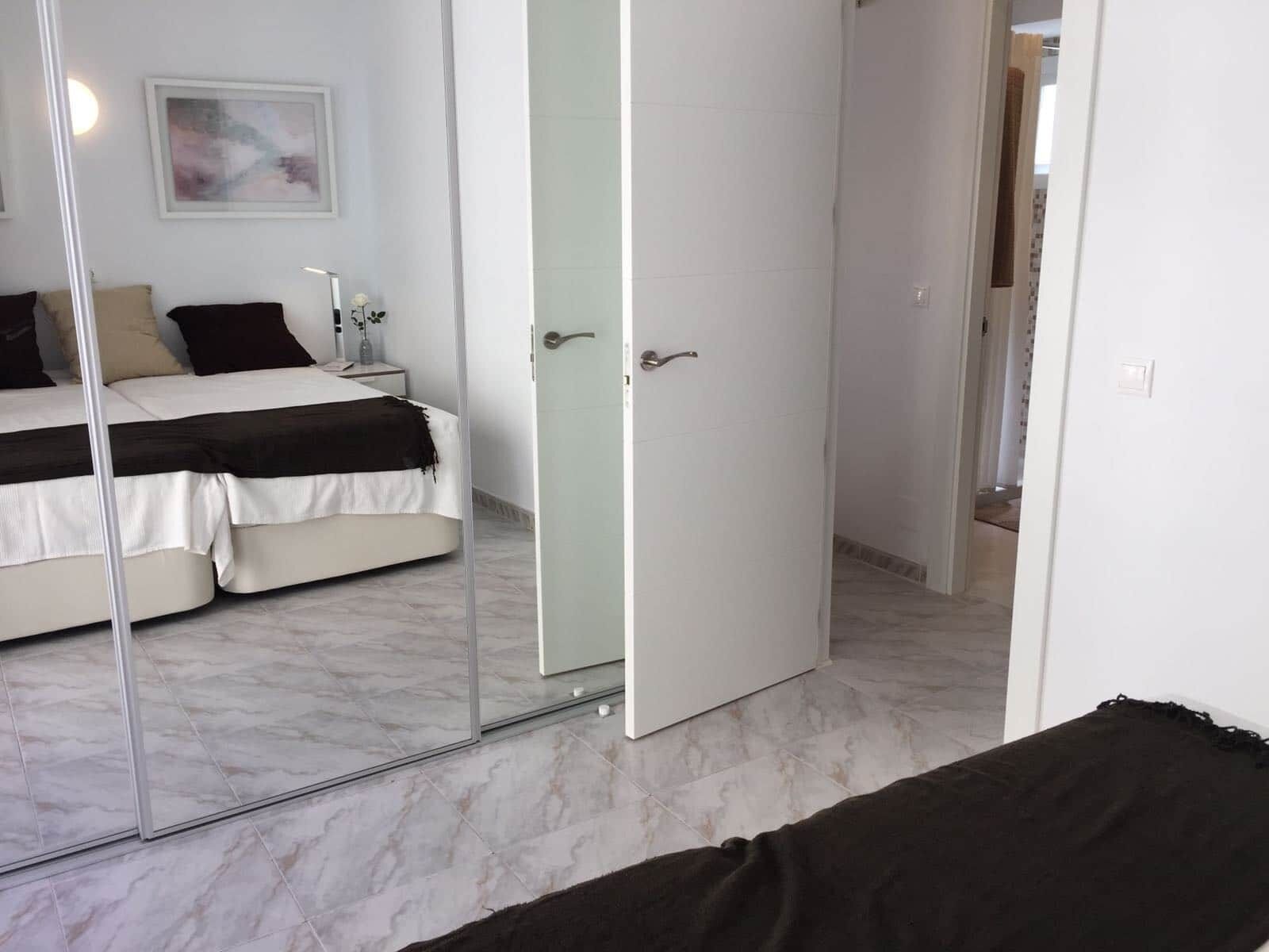 Un dormitorio con cama, mesita de noche y espejo.
