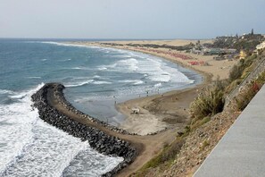 A coastal road with a rocky barrier and beach on the right. - Mini Studio Near the Beach in Playa del Ingles (San Bartolomé de Tirajana)