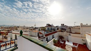 A rooftop terrace with a pool, potted plants, and a view of the cityscape.