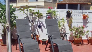 Two grey lounge chairs with potted plants and flowers around them. - Central Attic Apt Sleeps 4 With Patio (Almunecar)