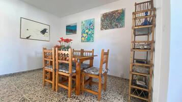 Un comedor con mesa y sillas de madera, suelo de baldosas y una estantería de bambú.