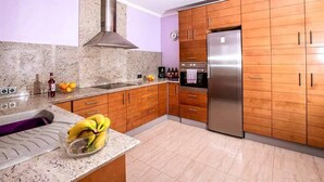 A kitchen with granite countertops, wooden cabinets, a stainless steel refrigerator, and a gas stove. - Costa Blanca, Private Pool, Full Aircon, Sleeps 12 (Benimeli)