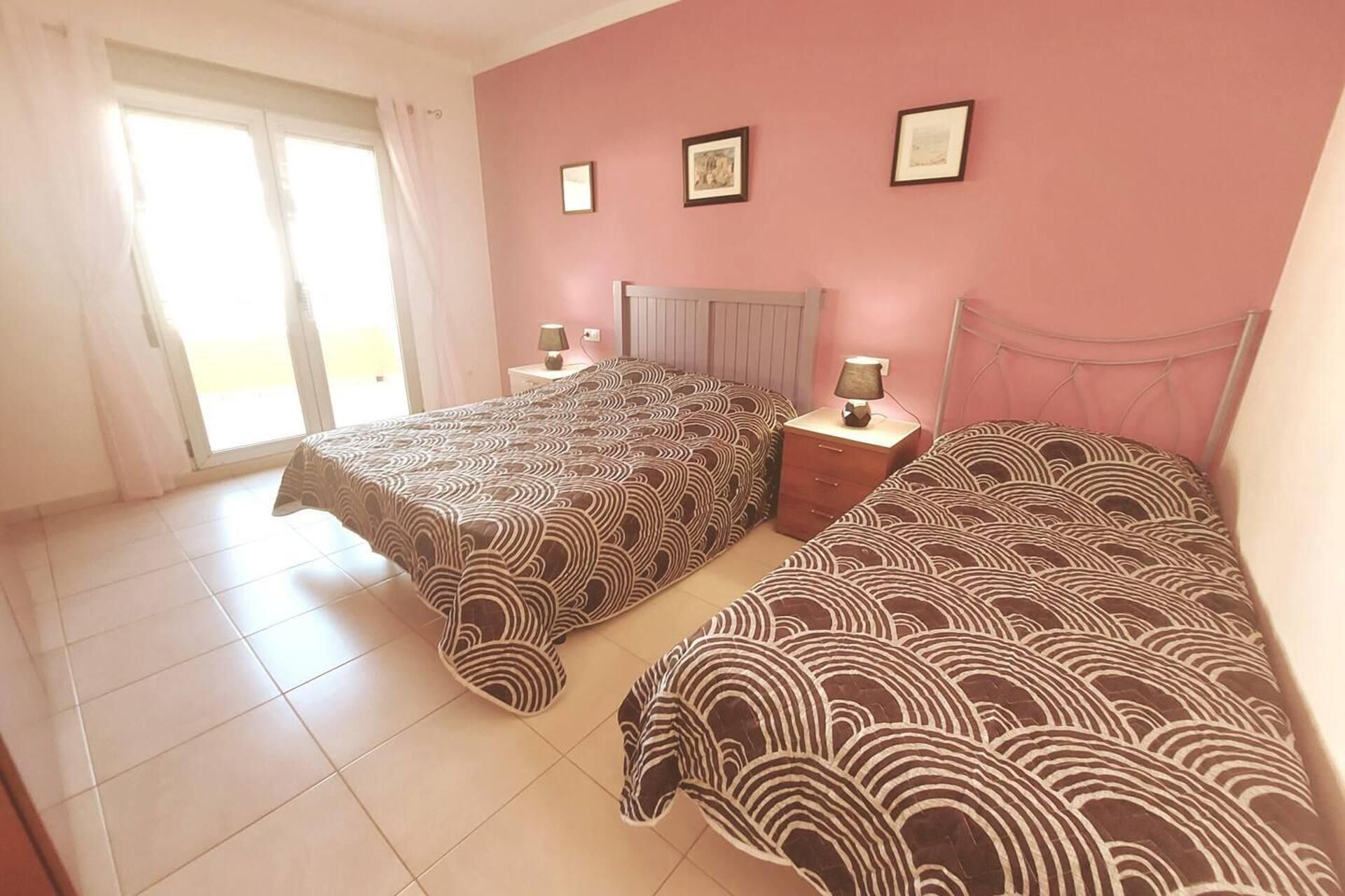 Une chambre avec deux lits, une fenêtre avec des rideaux et une porte.