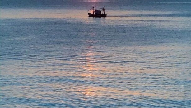 Ein Boot auf ruhigem Wasser bei Sonnenuntergang.