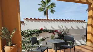 An outdoor patio with a round table and two chairs, surrounded by potted plants and a palm tree. - Private Pool- Rooftop Terrace & Bbq- Aircon (Zurgena)