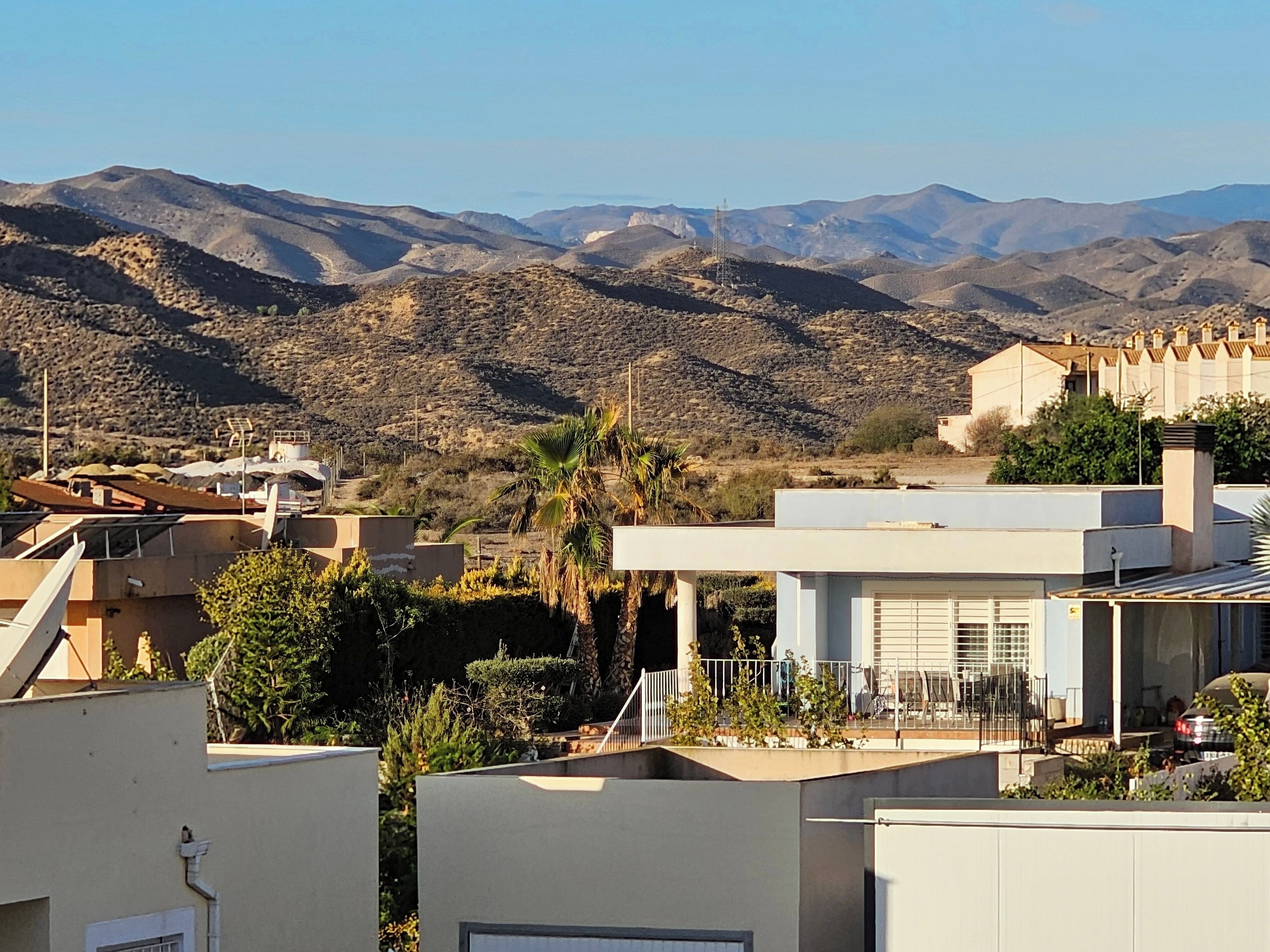 A residential area with modern houses, a clear view of distant mountains, and a few palm trees.