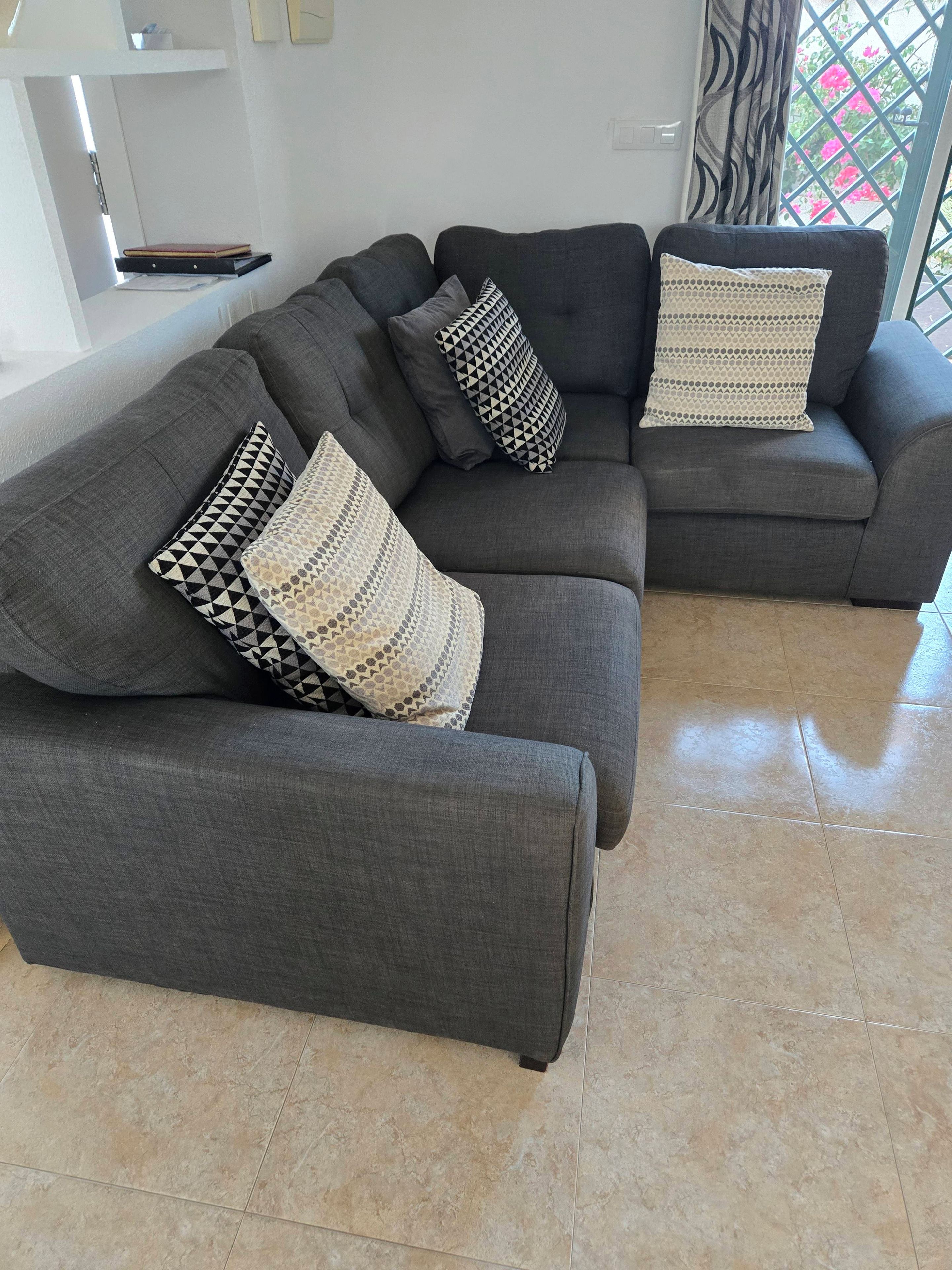 Un sofá modular con cojines estampados en un salón moderno con suelo de baldosas.