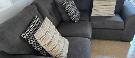 Un sofá modular con cojines estampados en un salón moderno con suelo de baldosas.