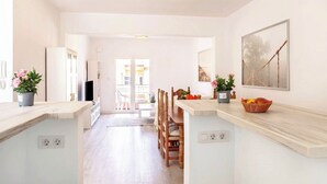 A bright, open-plan kitchen with a central island, wooden chairs, and a dining table. There are potted plants on the countertops and a painting on the wall. - Light-flooded Loft in Santa Cruz (Santa Cruz de Tenerife)