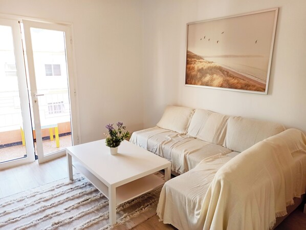 Ein Zimmer mit einem weißen Sofa, einem weißen Couchtisch und einem Vogelbild an der Wand.