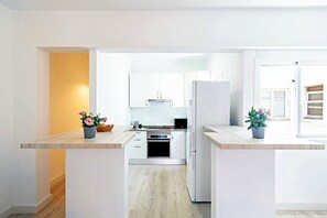 A modern kitchen with white cabinets, a built-in oven, and a refrigerator. There are two potted plants on the countertops. - Light-flooded Loft in Santa Cruz (Santa Cruz de Tenerife)