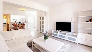 A modern living room with a white sofa, a coffee table, a TV on a white stand, and a bookshelf. - Light-flooded Loft in Santa Cruz (Santa Cruz de Tenerife)