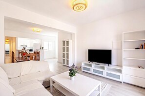 A modern living room with a white sofa, a coffee table, and a flat-screen TV on a white entertainment unit. - Light-flooded Loft in Santa Cruz (Santa Cruz de Tenerife)