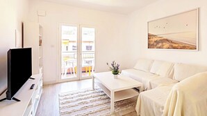 A modern living room with a flat-screen TV, a white sofa, a coffee table, and a painting on the wall. - Light-flooded Loft in Santa Cruz (Santa Cruz de Tenerife)