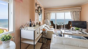 Ein Wohnzimmer mit Meerblick, einer Couch, einem Couchtisch und einem Fernseher.