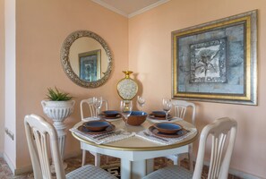 A dining area with a round table set for four, surrounded by white chairs.