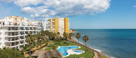 A resort with multiple buildings, a swimming pool, and a beach view.