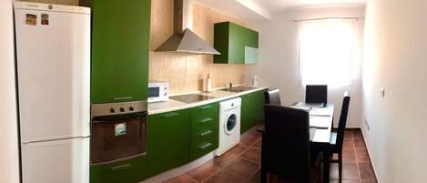 A compact kitchen with a refrigerator, oven, microwave, and washing machine.