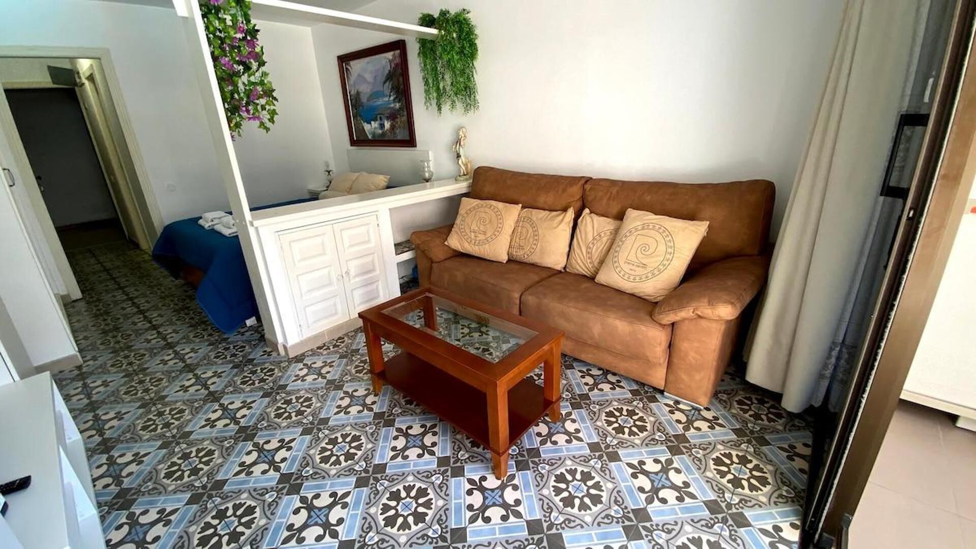 Un salon avec un canapé marron, une table basse et des carreaux de sol à motifs.