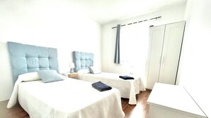 Ein Hotelzimmer mit zwei Betten, einem Kleiderschrank und einem Schreibtisch.