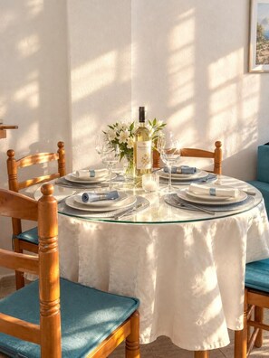 A round dining table with a white tablecloth, set with plates, glasses, and a bottle of wine. - Godisa 18 Apartment Playa del Cura Torrevieja! (Torrevieja)