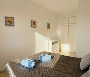 A bedroom with a bed, two pillows, a dresser, and three wall-mounted paintings. - Godisa 18 Apartment Playa del Cura Torrevieja! (Torrevieja)