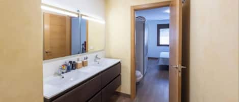 Une salle de bain moderne avec un grand miroir, deux vasques et un plancher en bois.