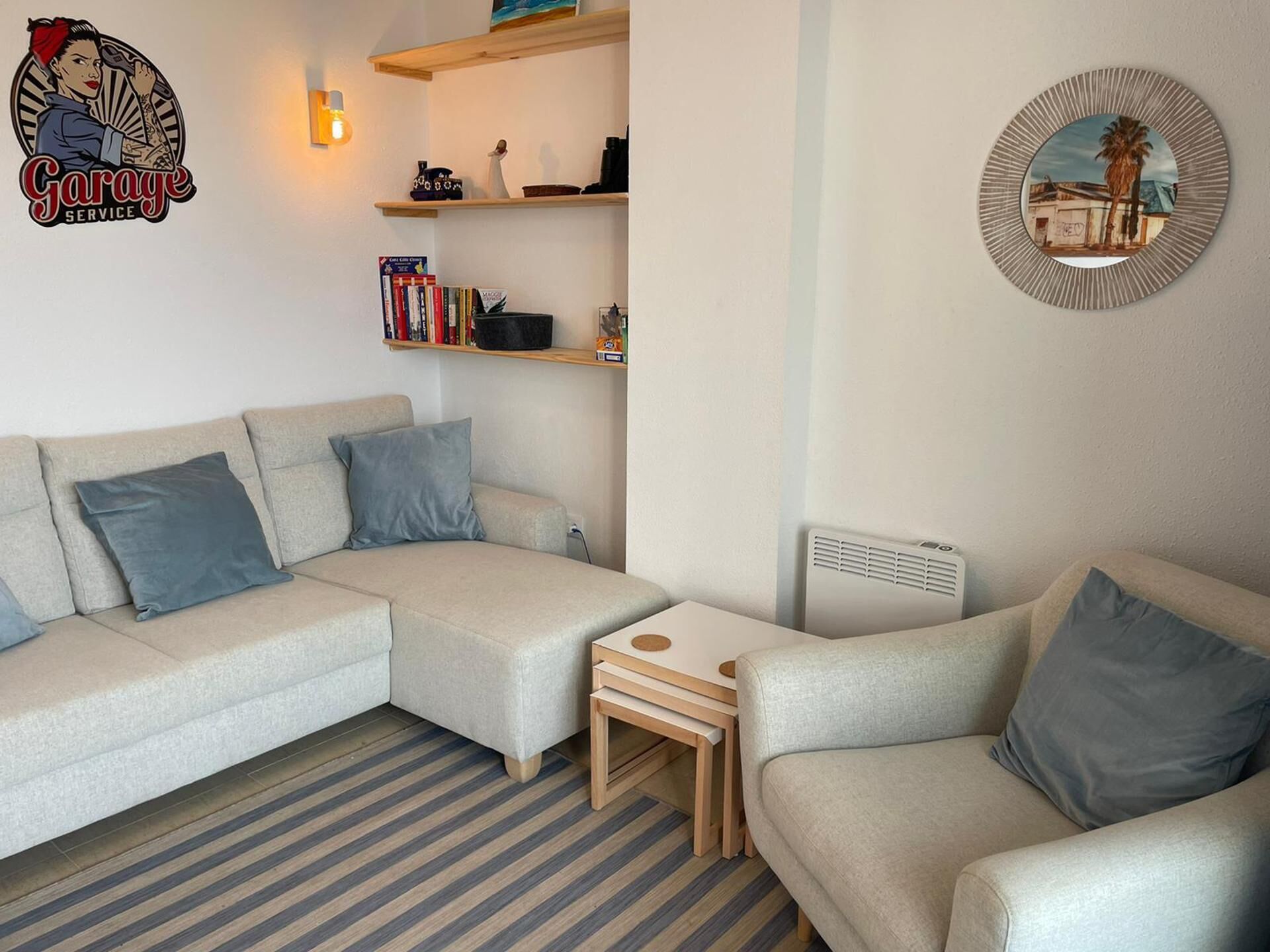 A living room with a sofa set, a coffee table, a bookshelf, and a wall-mounted radiator.