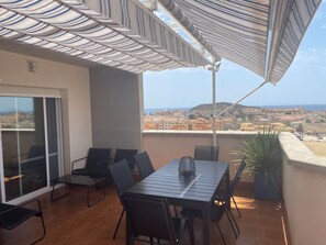 Ein Balkon mit Tisch, Stühlen, einem Blumentopf und Blick auf eine Stadtlandschaft.