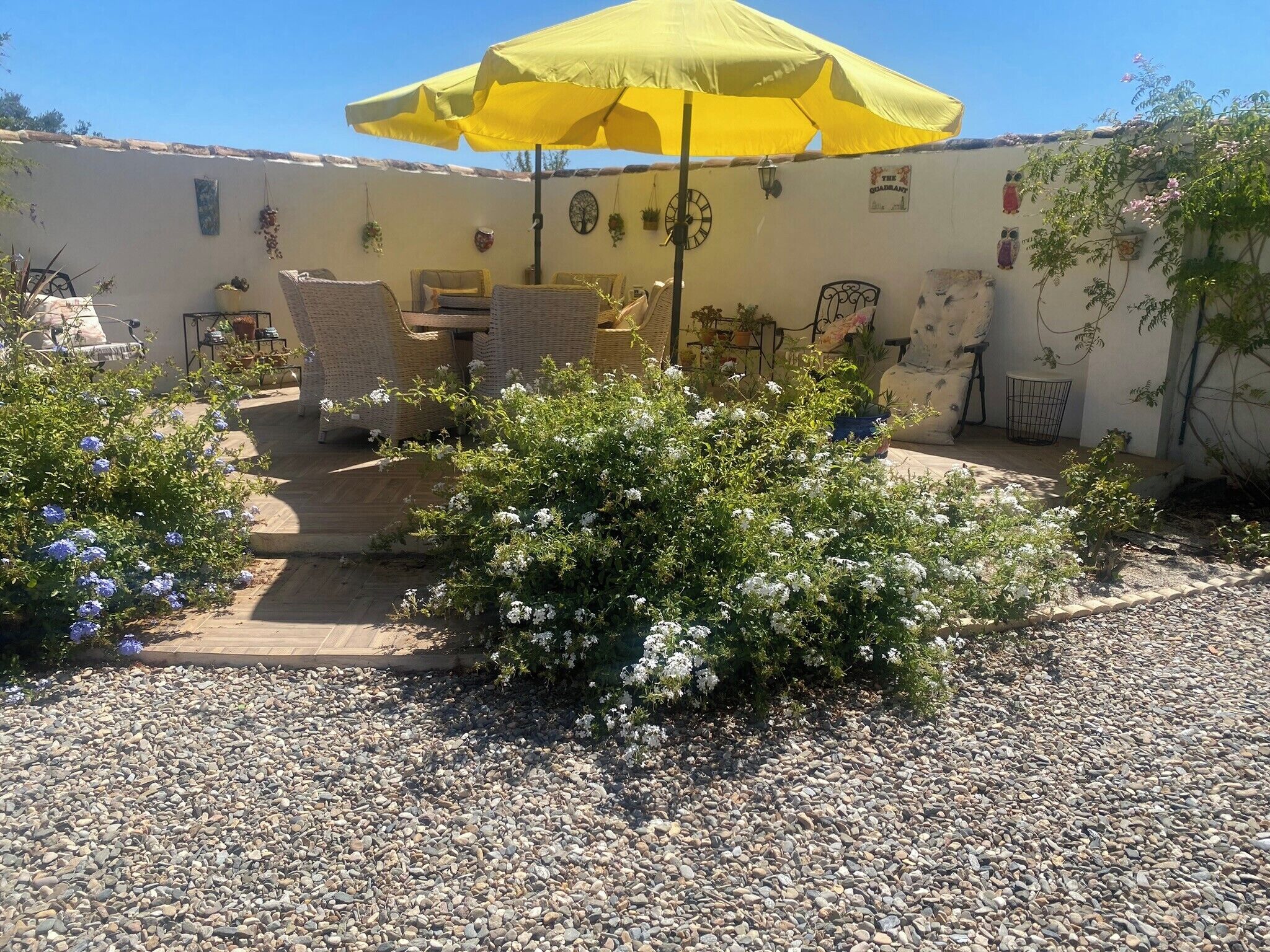 A patio area with a yellow umbrella, wicker furniture, and potted plants.