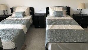 A double room with two beds, each with a nightstand and a lamp.