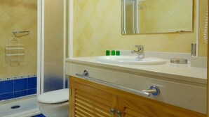 Une salle de bain avec douche, toilettes et lavabo.