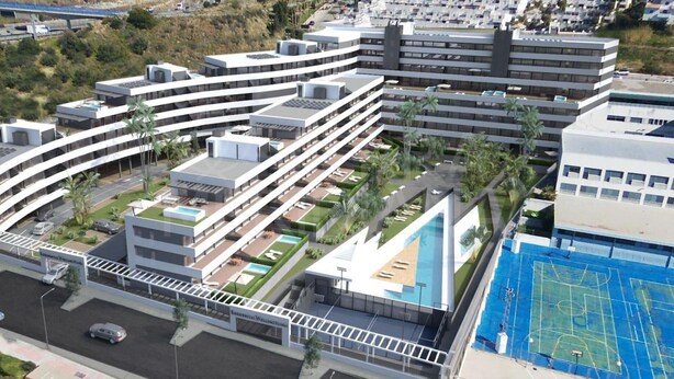 A modern multi-story building with a curved roofline, a rooftop pool, and a sports court. - Stunning Apartment in Estepona, Spain Private Pool (Estepona)