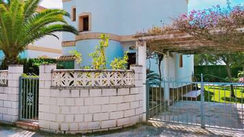 Stunning residential building with a gated entrance, balcony, and beautifully manicured garden.