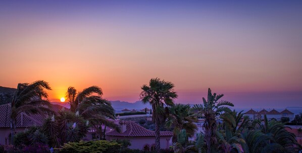 A sunset view over a resort with palm trees and buildings with red-tiled roofs. - Villa el Palmar With 3 Bedrooms Close to the Beach (Denia)