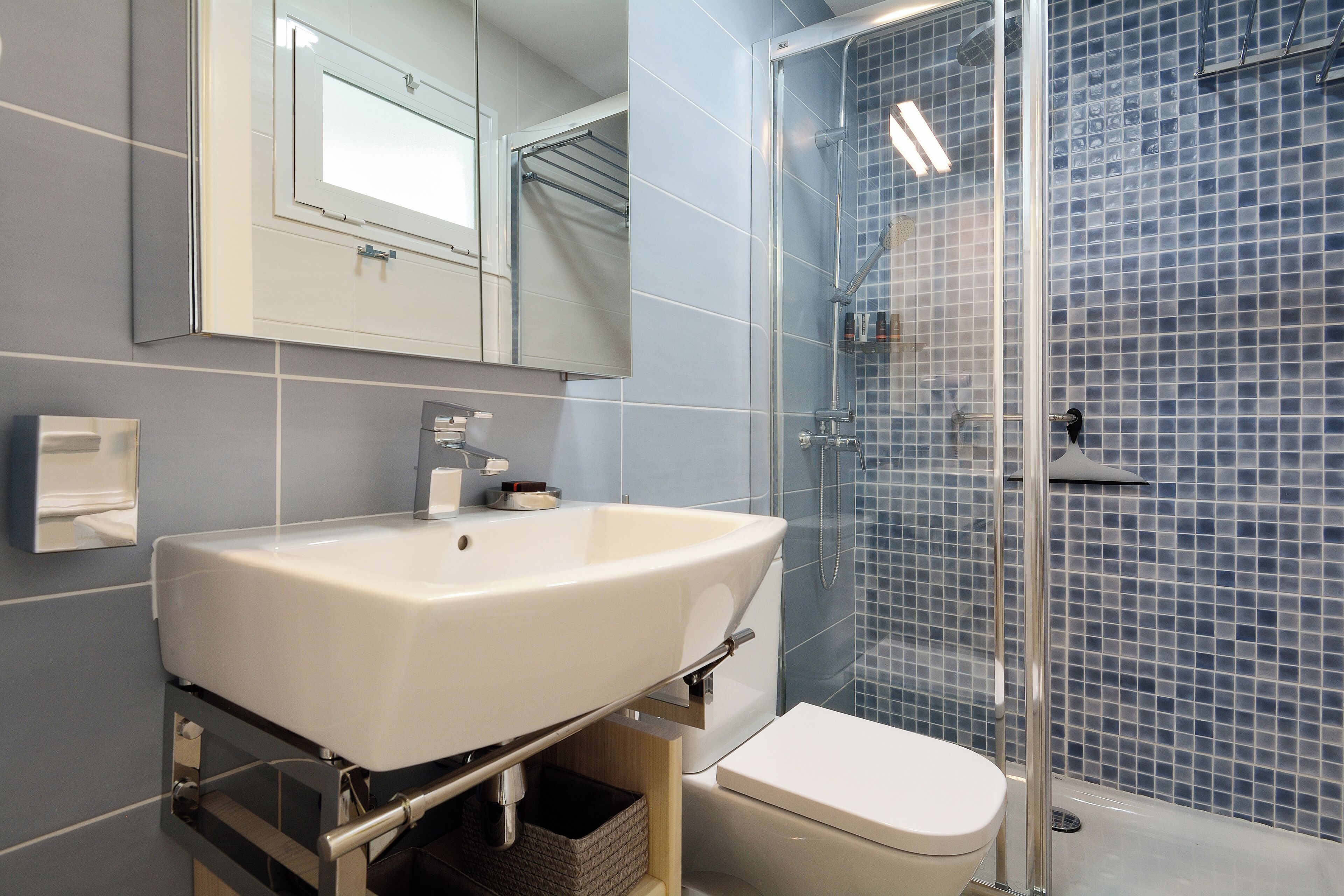A bathroom with a white sink, a toilet, and a glass shower enclosure.