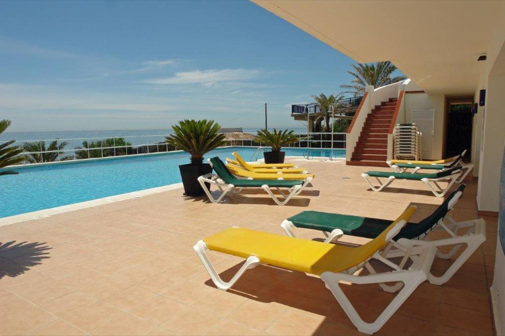A poolside area with sun loungers and a view of the sea.