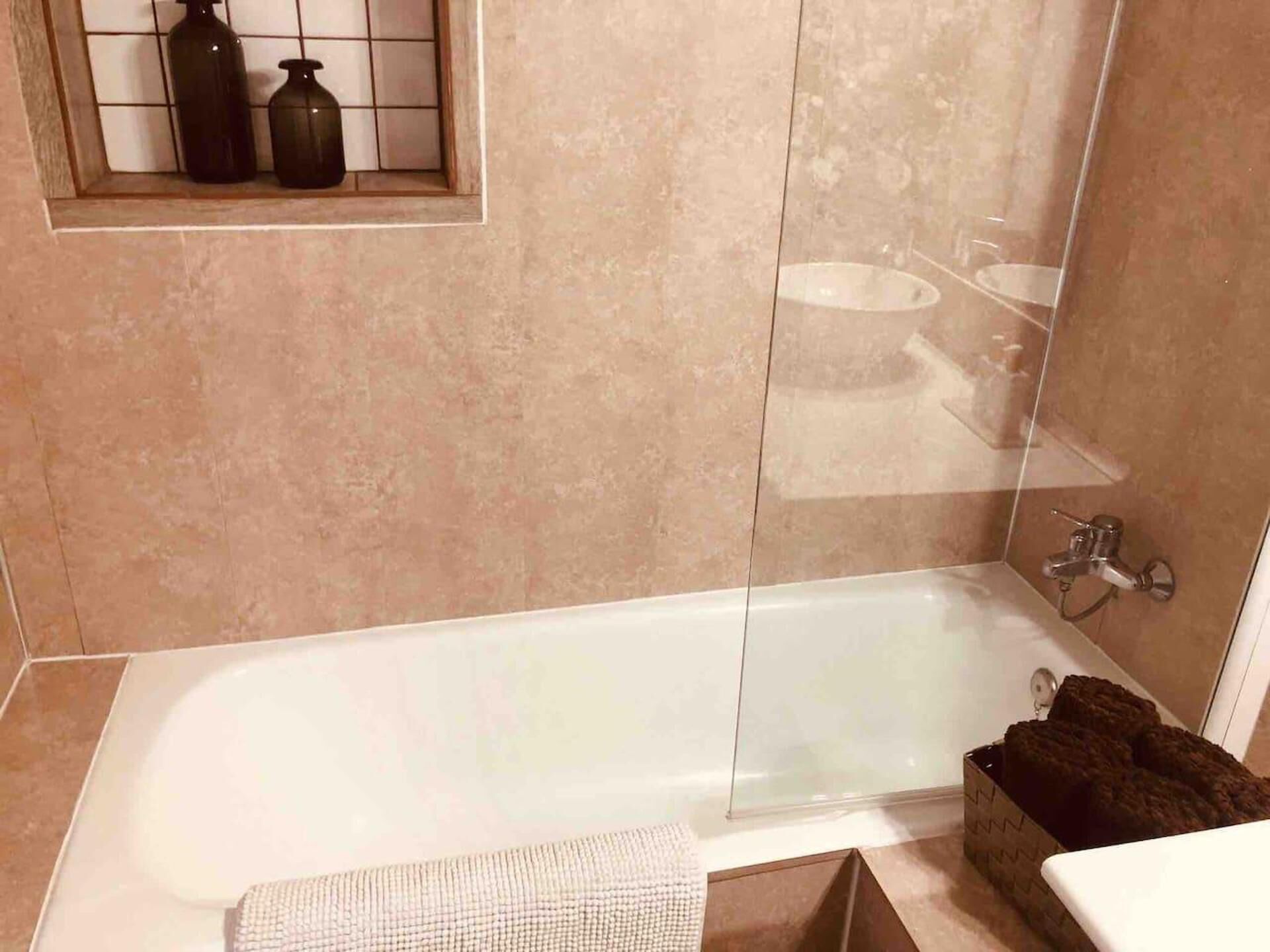 Un baño con bañera, lavamanos y una ventana con botellas.