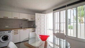 A modern kitchen with white cabinets, a washing machine, and a glass table with chairs. - Lovely Studio in Costa del Silencio Chayofita (Arona)